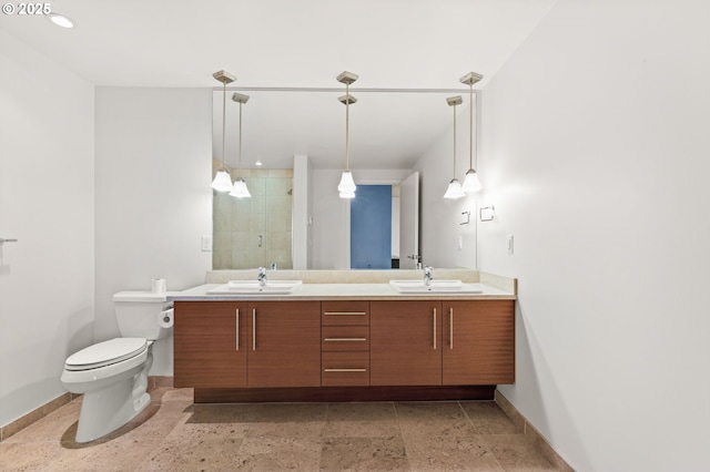 full bathroom with a sink, a shower stall, baseboards, and double vanity