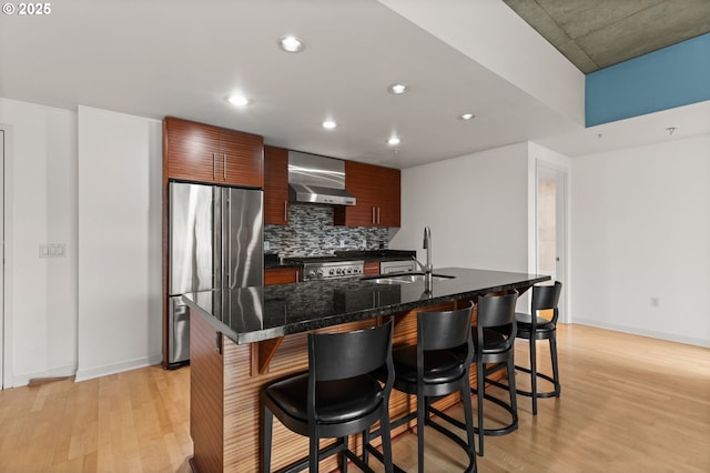 kitchen with stainless steel fridge, modern cabinets, a breakfast bar area, stove, and wall chimney range hood