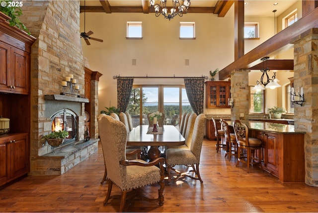16465 Suntree Ln, Sisters, OR 97759 - dining room with a high ceiling, a stone fireplace, beamed ceiling, hardwood / wood-style floors, and a chandelier