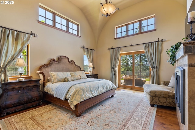 16465 Suntree Ln, Sisters, OR 97759 - bedroom featuring access to exterior, wood finished floors, high vaulted ceiling, and a tile fireplace