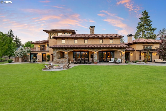 16465 Suntree Ln, Sisters, OR 97759 - back of house at dusk with a chimney, a lawn, and a patio area