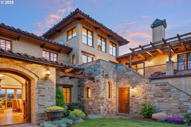 16465 Suntree Ln, Sisters, OR 97759 - back of house at dusk with stone siding, stucco siding, and a tiled roof