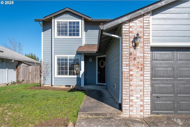 property entrance with a garage, fence, a lawn, and brick siding