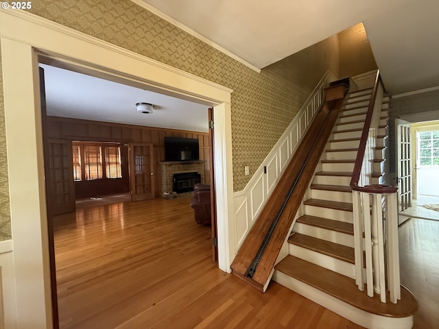 880 E 2nd St, Coquille, OR 97423 - stairway with a brick fireplace, wood finished floors, ornamental molding, wallpapered walls, and wainscoting