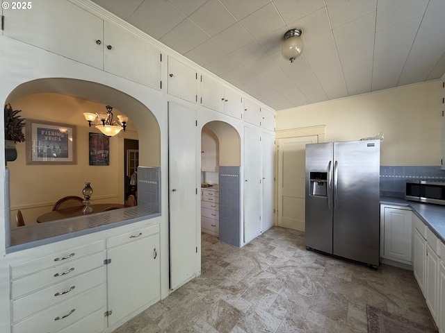 880 E 2nd St, Coquille, OR 97423 - kitchen with appliances with stainless steel finishes, arched walkways, dark countertops, white cabinetry, and stone finish floors