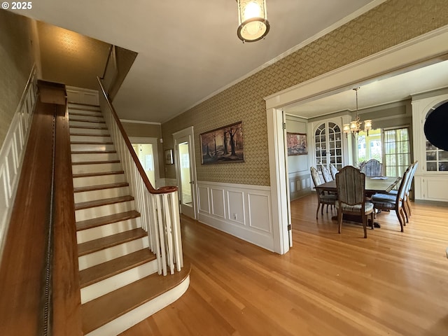 880 E 2nd St, Coquille, OR 97423 - stairway featuring ornamental molding, wallpapered walls, a decorative wall, wood finished floors, and a chandelier