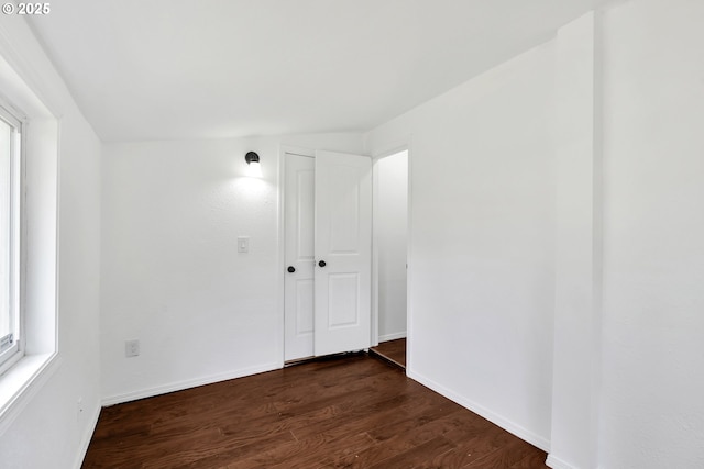empty room with baseboards and dark wood-type flooring