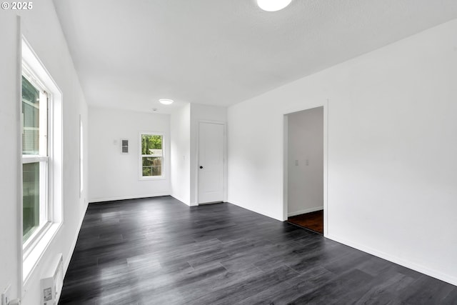 unfurnished room with baseboards and dark wood-type flooring