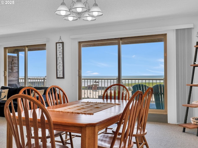 1146 N Marion Ave Unit 628, Gearhart, OR 97138 - dining room featuring a chandelier, carpet, a textured ceiling, and a water view