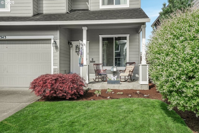 entrance to property with a garage, covered porch, a shingled roof, and a lawn