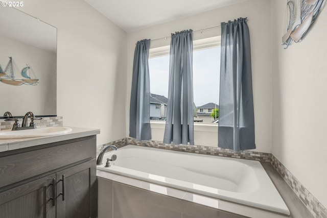 bathroom with vanity, decorative backsplash, and a bath