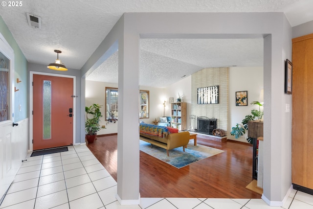 tiled foyer featuring a textured ceiling, a brick fireplace, and lofted ceiling