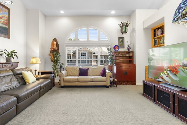 carpeted living room with high vaulted ceiling and plenty of natural light