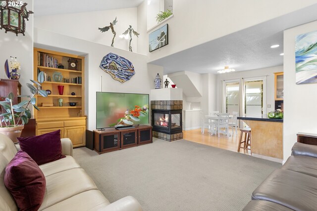 living room featuring ceiling fan, lofted ceiling, a fireplace, and carpet flooring