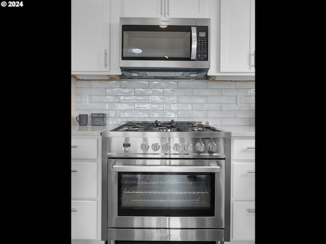 1790 Thompson Falls Dr, Seaside, OR 97138 - kitchen featuring stainless steel appliances, white cabinetry, decorative backsplash, and light stone countertops
