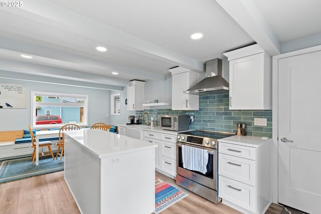 2385 S Downing St, Seaside, OR 97138 - kitchen featuring stainless steel appliances, wall chimney exhaust hood, light wood-type flooring, light countertops, and beamed ceiling