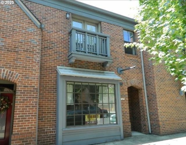 back of house with a balcony and brick siding