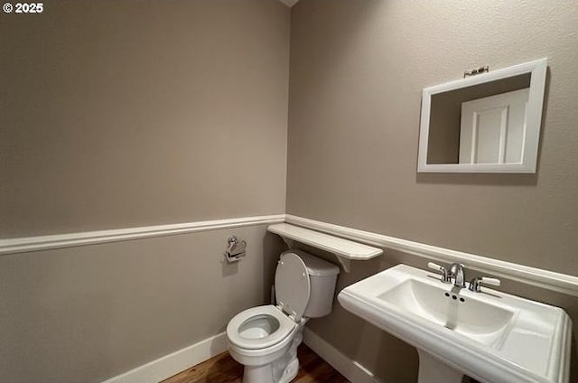 bathroom with wood finished floors, a sink, toilet, and baseboards