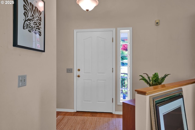 foyer entrance with healthy amount of natural light, wood finished floors, and baseboards