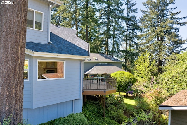 view of side of home with a shingled roof and a wooden deck