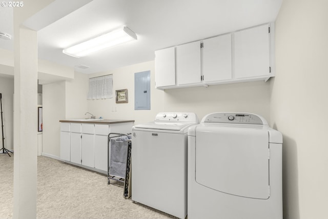 laundry room featuring washing machine and clothes dryer, cabinet space, electric panel, and a sink