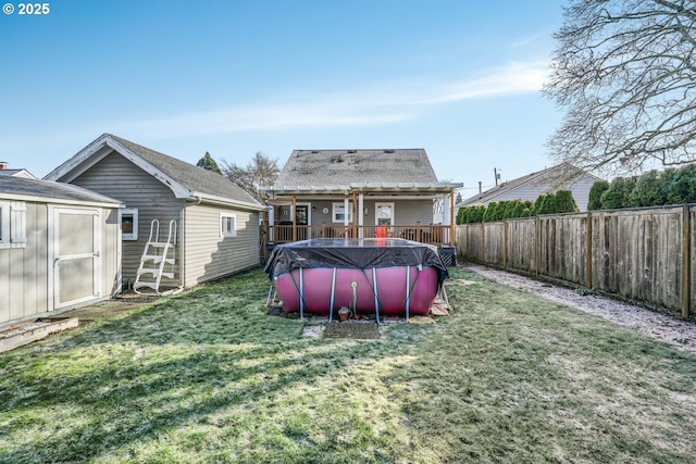 back of house with a fenced in pool, a lawn, a storage shed, a fenced backyard, and an outbuilding