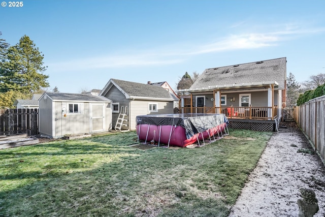 back of house featuring a deck, a fenced backyard, a shed, an outdoor structure, and a fenced in pool