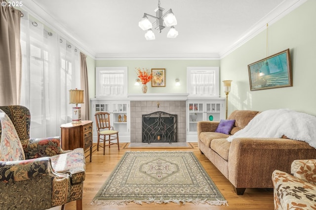 living area featuring a tile fireplace, wood finished floors, an inviting chandelier, and ornamental molding