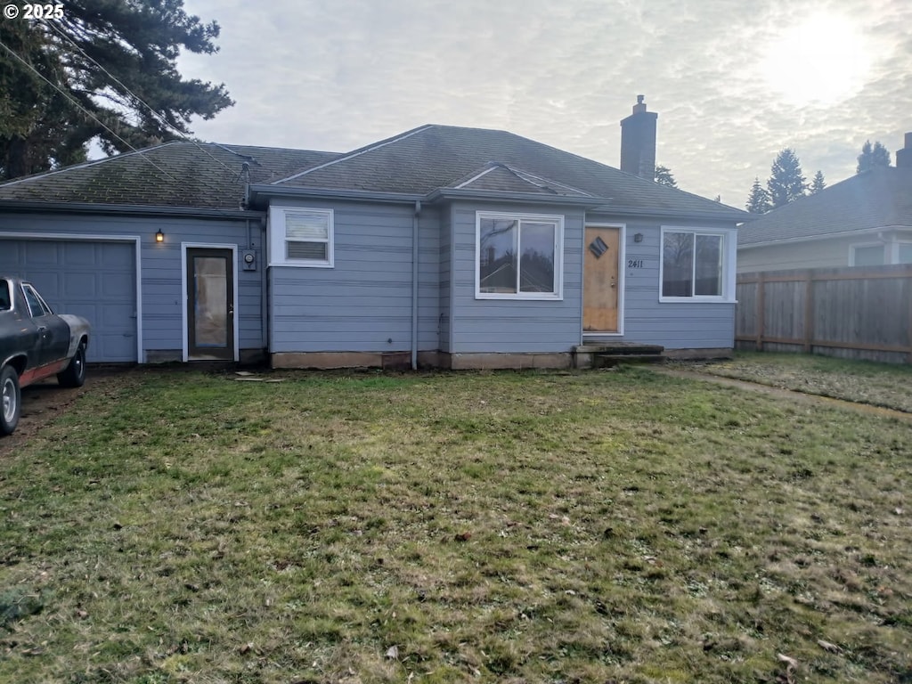 rear view of property with a garage and a yard