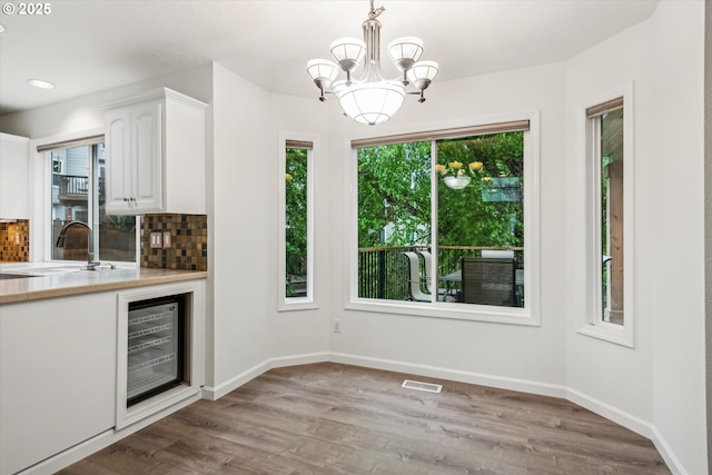 bar area featuring a sink, wine cooler, wood finished floors, decorative backsplash, and recessed lighting