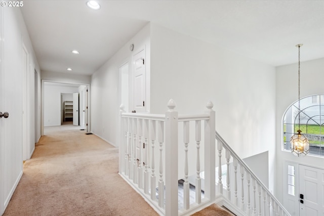 hall with a chandelier, an upstairs landing, recessed lighting, light colored carpet, and baseboards