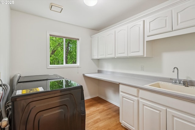 laundry room with cabinet space, light wood-type flooring, washing machine and dryer, baseboards, and a desk