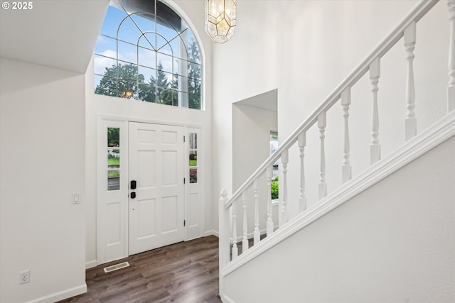 foyer with a towering ceiling, wood finished floors, stairs, baseboards, and a chandelier