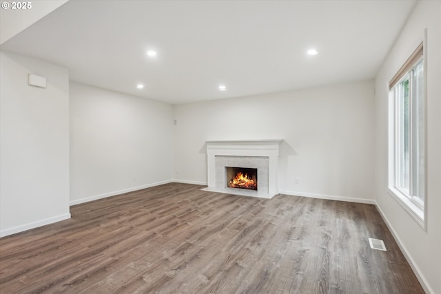 unfurnished living room featuring wood finished floors, a fireplace, recessed lighting, and baseboards