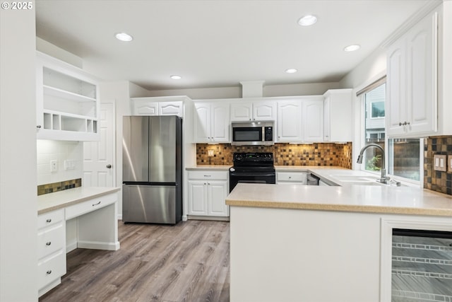 kitchen featuring stainless steel appliances, a sink, backsplash, a peninsula, and recessed lighting