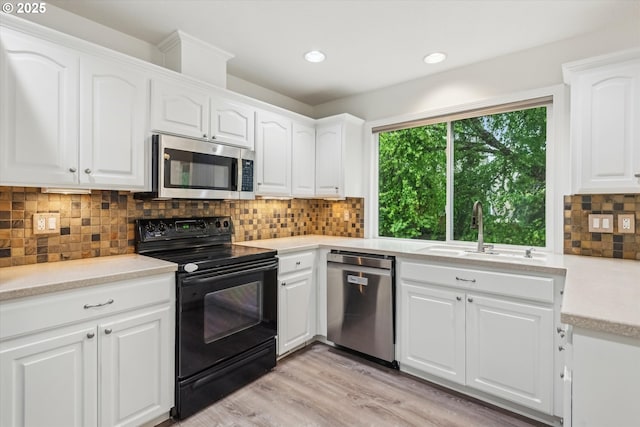 kitchen with appliances with stainless steel finishes, a sink, light countertops, white cabinetry, and decorative backsplash