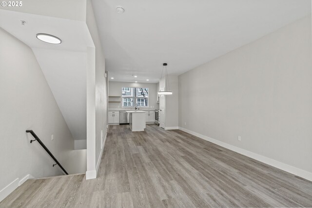 unfurnished living room featuring recessed lighting, baseboards, light wood finished floors, and a sink