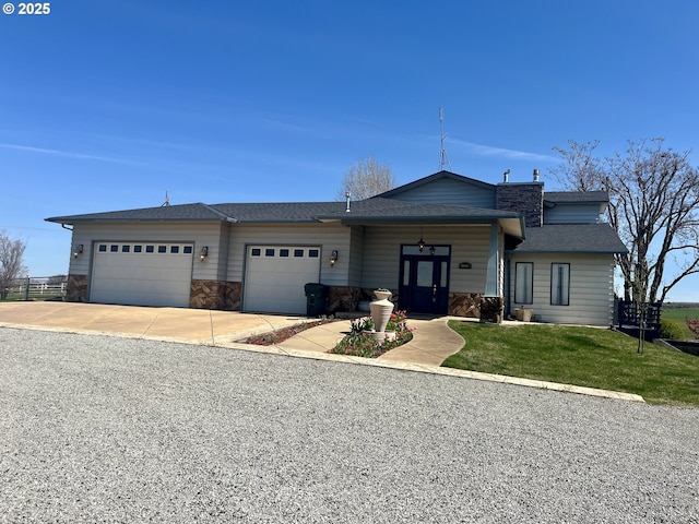 view of front of property with roof with shingles, a front yard, stone siding, an attached garage, and concrete driveway