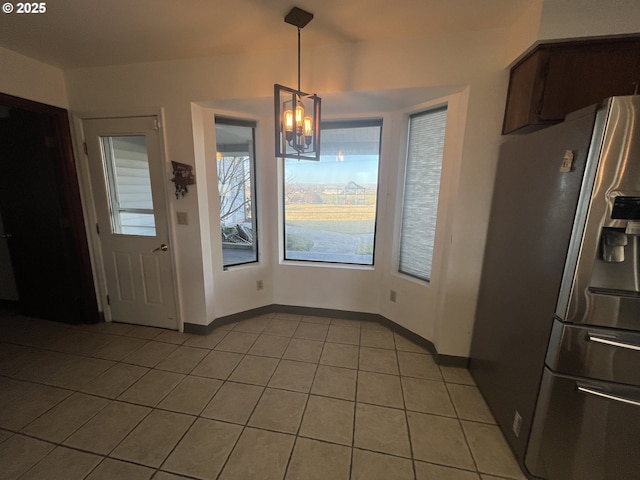 unfurnished dining area with a chandelier, light tile patterned floors, and baseboards