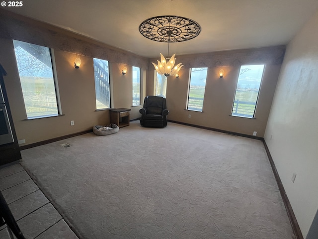 unfurnished room featuring carpet floors, a wealth of natural light, a notable chandelier, and baseboards