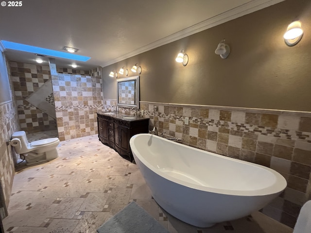 full bath featuring a freestanding tub, double vanity, ornamental molding, tile walls, and a sink