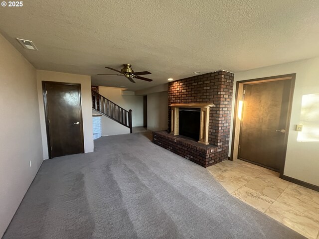 unfurnished living room featuring a brick fireplace, visible vents, stairway, and light colored carpet