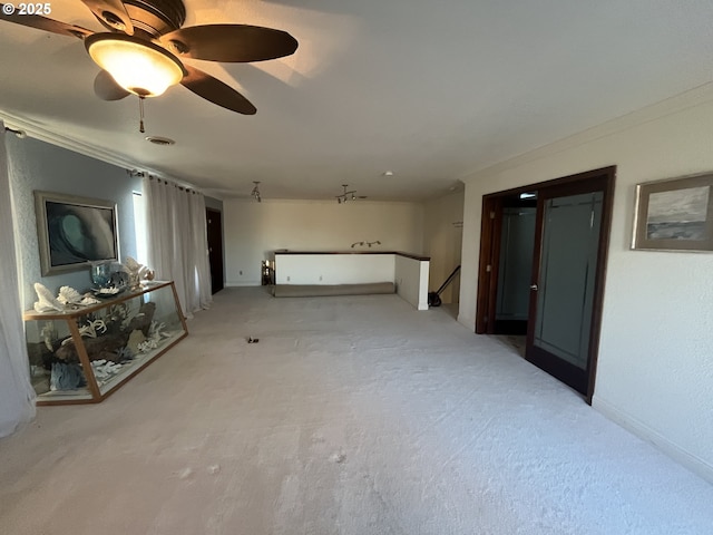 unfurnished living room featuring ornamental molding, baseboards, a ceiling fan, and light colored carpet