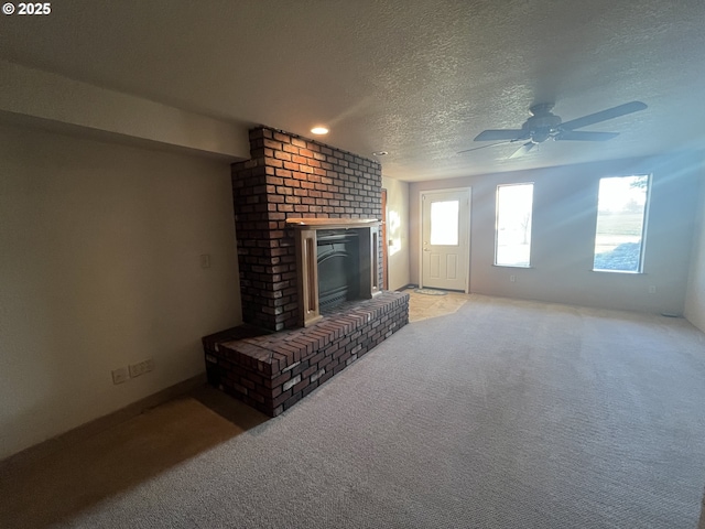 unfurnished living room with light carpet, a brick fireplace, a textured ceiling, and ceiling fan