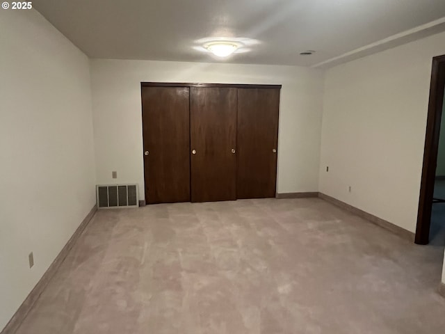 unfurnished bedroom featuring a closet, light colored carpet, baseboards, and visible vents