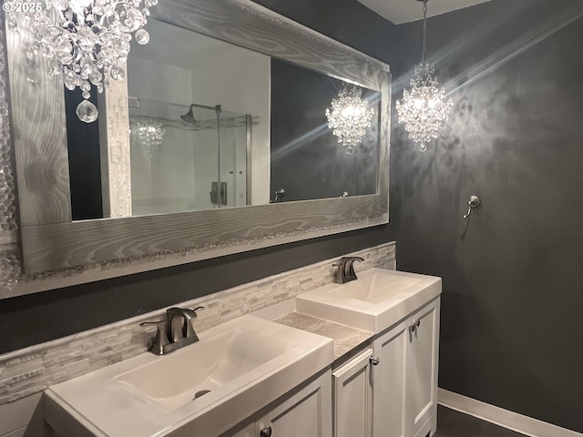 bathroom with double vanity, a stall shower, baseboards, and a sink