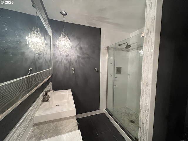 bathroom with a shower stall, a notable chandelier, baseboards, and a sink