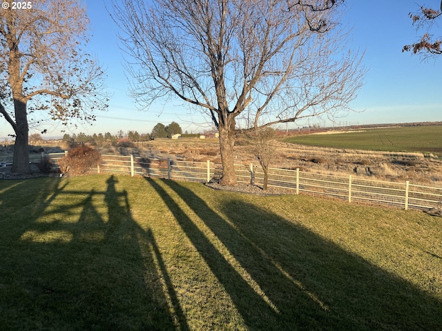 view of yard with fence and a rural view