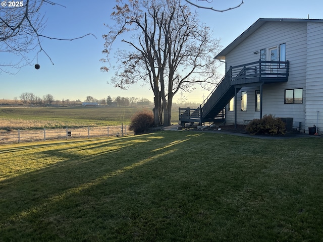 view of yard featuring a rural view, central air condition unit, fence, and stairs