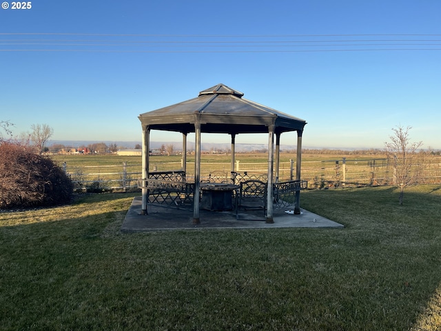 view of yard with a rural view, fence, a gazebo, and a patio